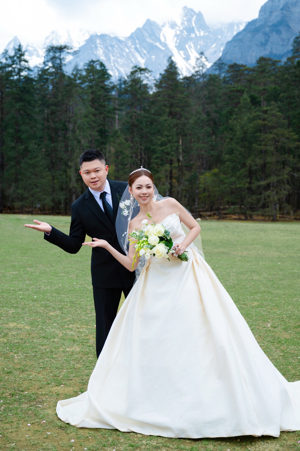 Tyler and Emmy in wedding attire on a meadow with mountains